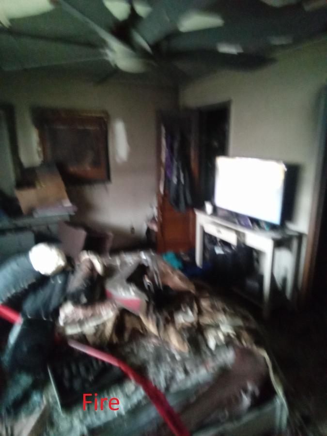 Fire damaged living room with burned ceiling and debris — fire restoration Panama City