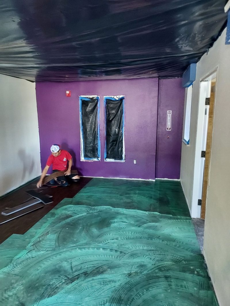 SRP crew member installing luxury vinyl plank flooring with containment barriers