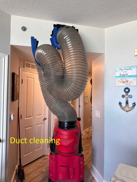 Red negative air machine with flex hose connected to ceiling duct for professional air duct cleaning