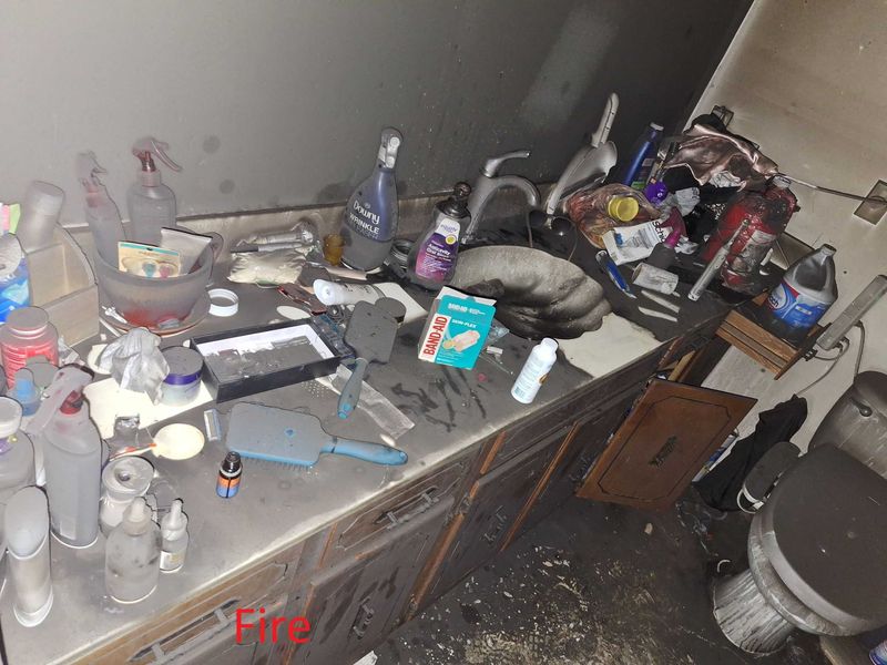Fire-damaged bathroom vanity covered in soot and melted debris